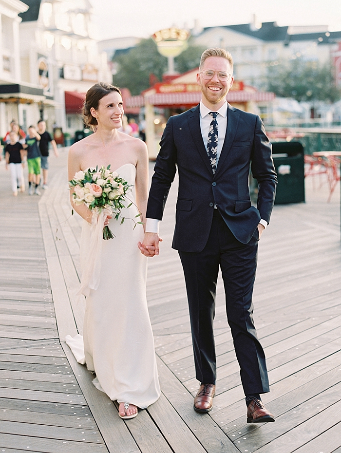 bride and groom walking hand in hand down the disney boardwalk orlando