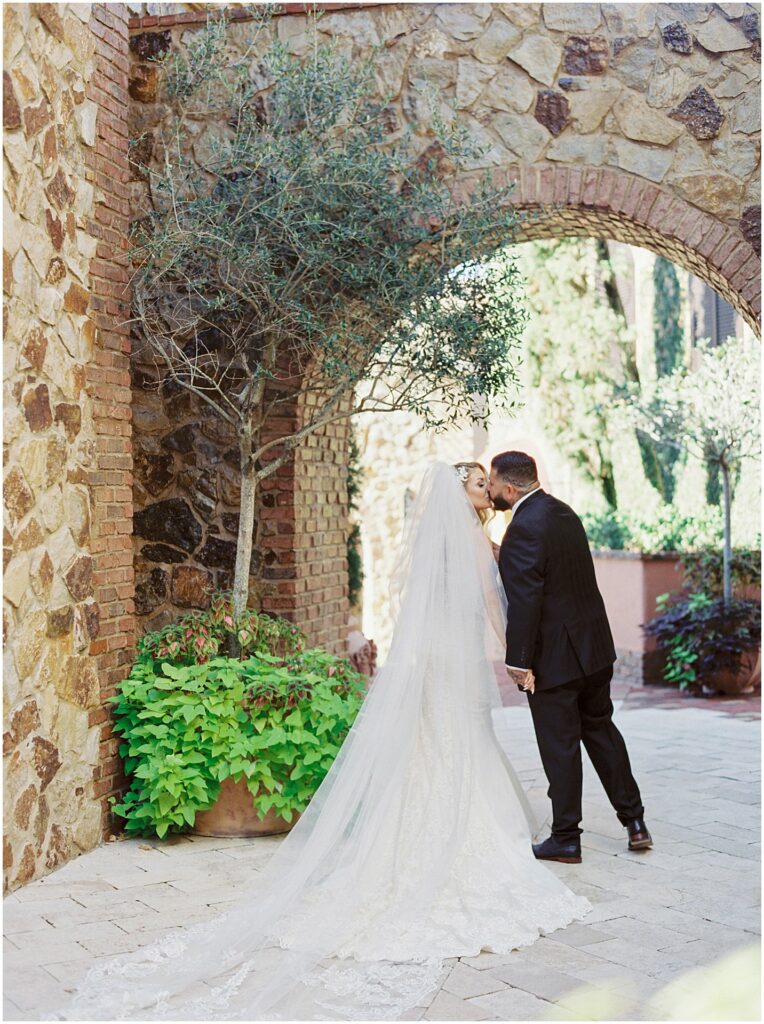 bride and groom kissing under archway at Bella Collina Orlando Wedding
