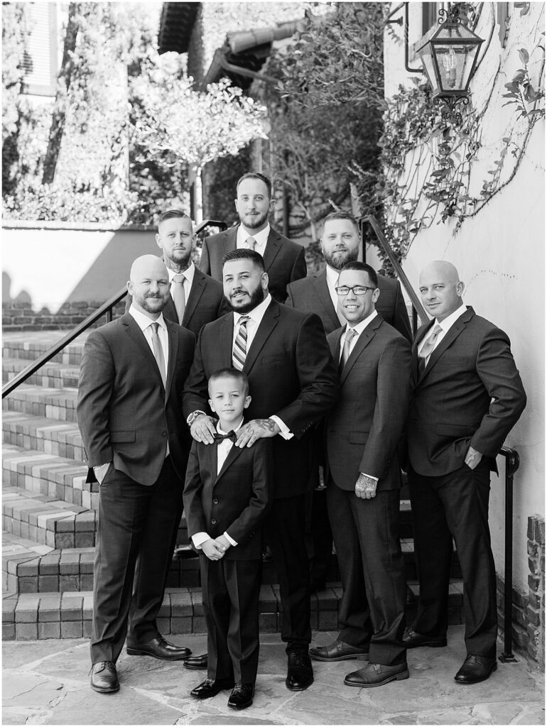 groom and groomsmen lined up on staircase smiling for black and white portraits at at Bella Collina Orlando Wedding