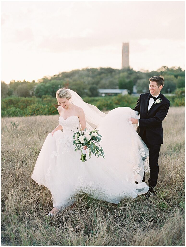 bride and groom walk through grassy field at Bok Tower gardens wedding