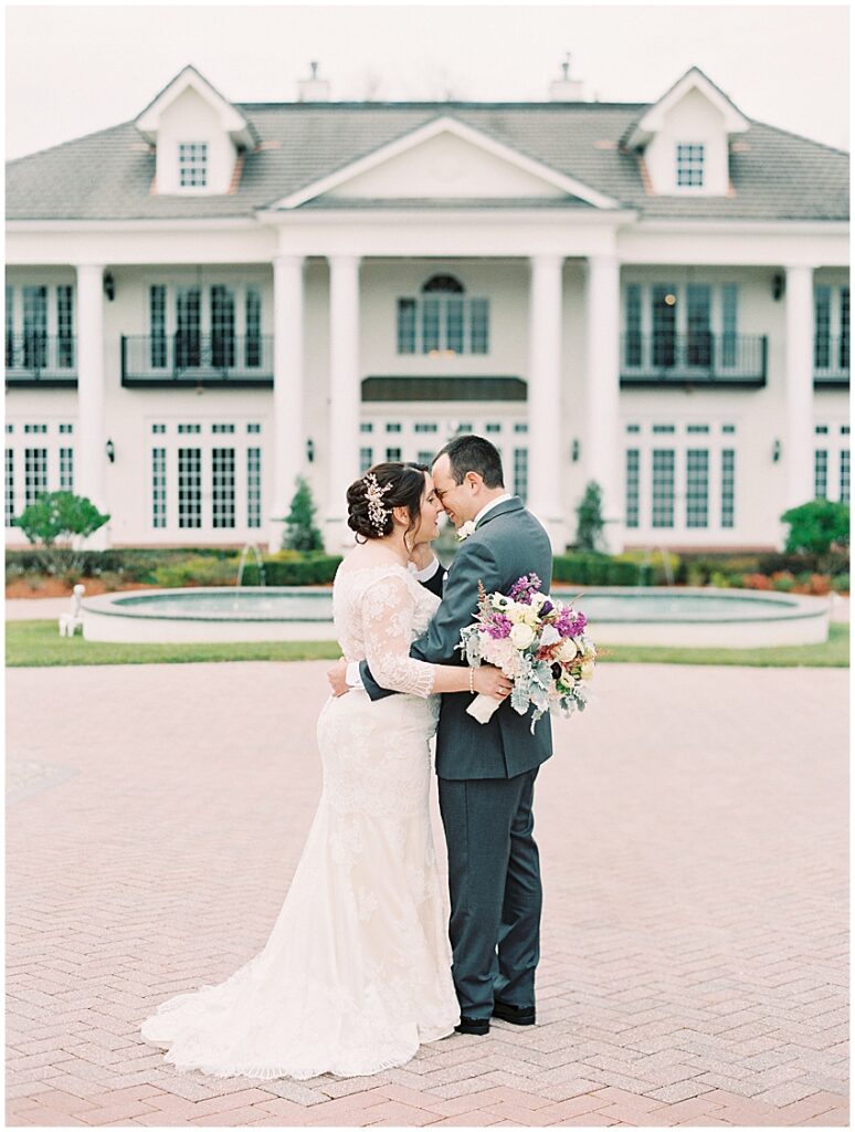 couple hold heads together in front of luxmore grande estate orlando wedding