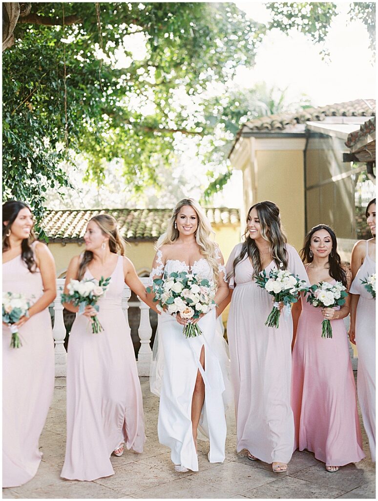 bride and bridesmaids walk towards camera smiling and laughing at the Addison in boca grande Miami wedding photographer
