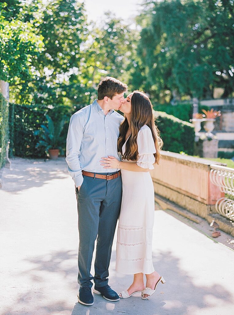 A couple kisses on the grounds of Vizcaya Museum and Gardens during their engagement session with Kt Crabb Photography